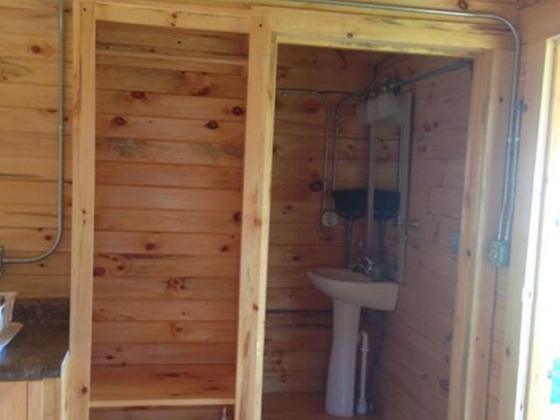 Small cabin bathroom with a pedestal sink, seen through an open doorway